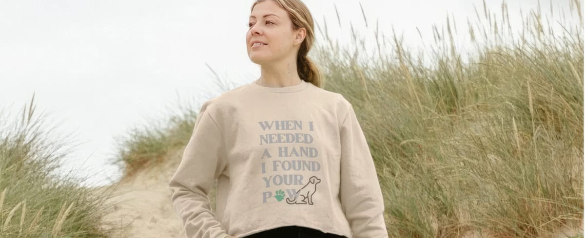 Woman on the beach wearing an ability dogs jumper