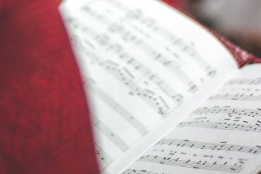 person signing in church holding open a song book by david beale