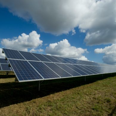 solar farm panels with blue sky and white fluffy clouds in the background