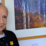 Karen Taggart standing by one of her autumnal paintings