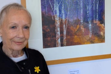 Karen Taggart standing by one of her autumnal paintings