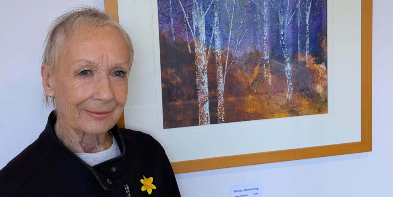 Karen Taggart standing by one of her autumnal paintings