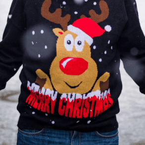 Man wearing a christmas jumper standing on the street in the snow