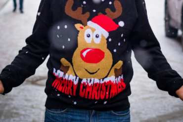 Man wearing a christmas jumper standing on the street in the snow