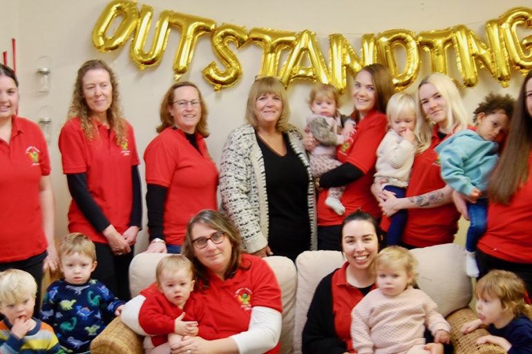 Staff and pupils at the Nursery with large gold balloon that reads 'Outstanding'