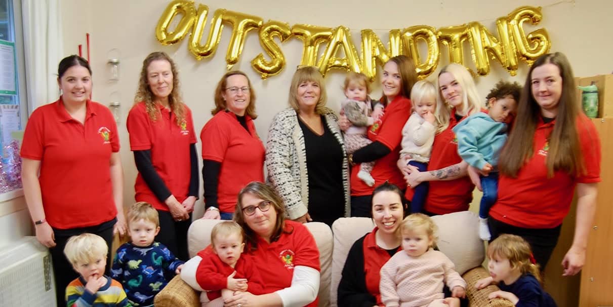 Staff and pupils at the Nursery with large gold balloon that reads 'Outstanding'