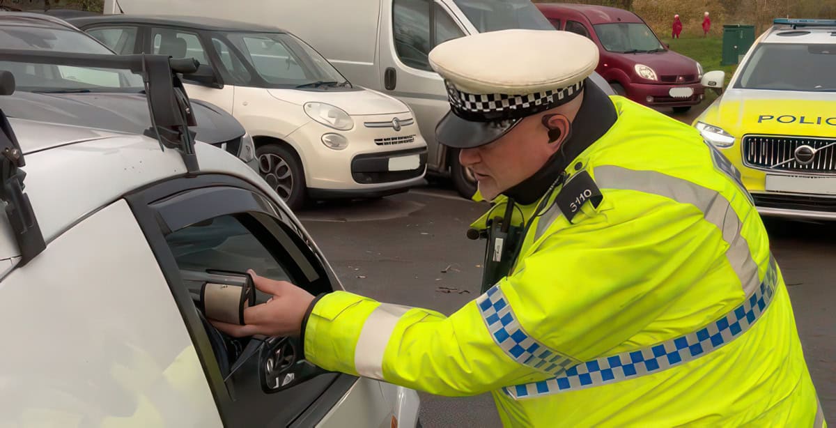 Police officer operating a breath test on a driver through the window-hq-width-1200px