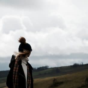 Woman standing on hill in strong wind