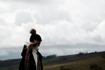 Woman standing on hill in strong wind