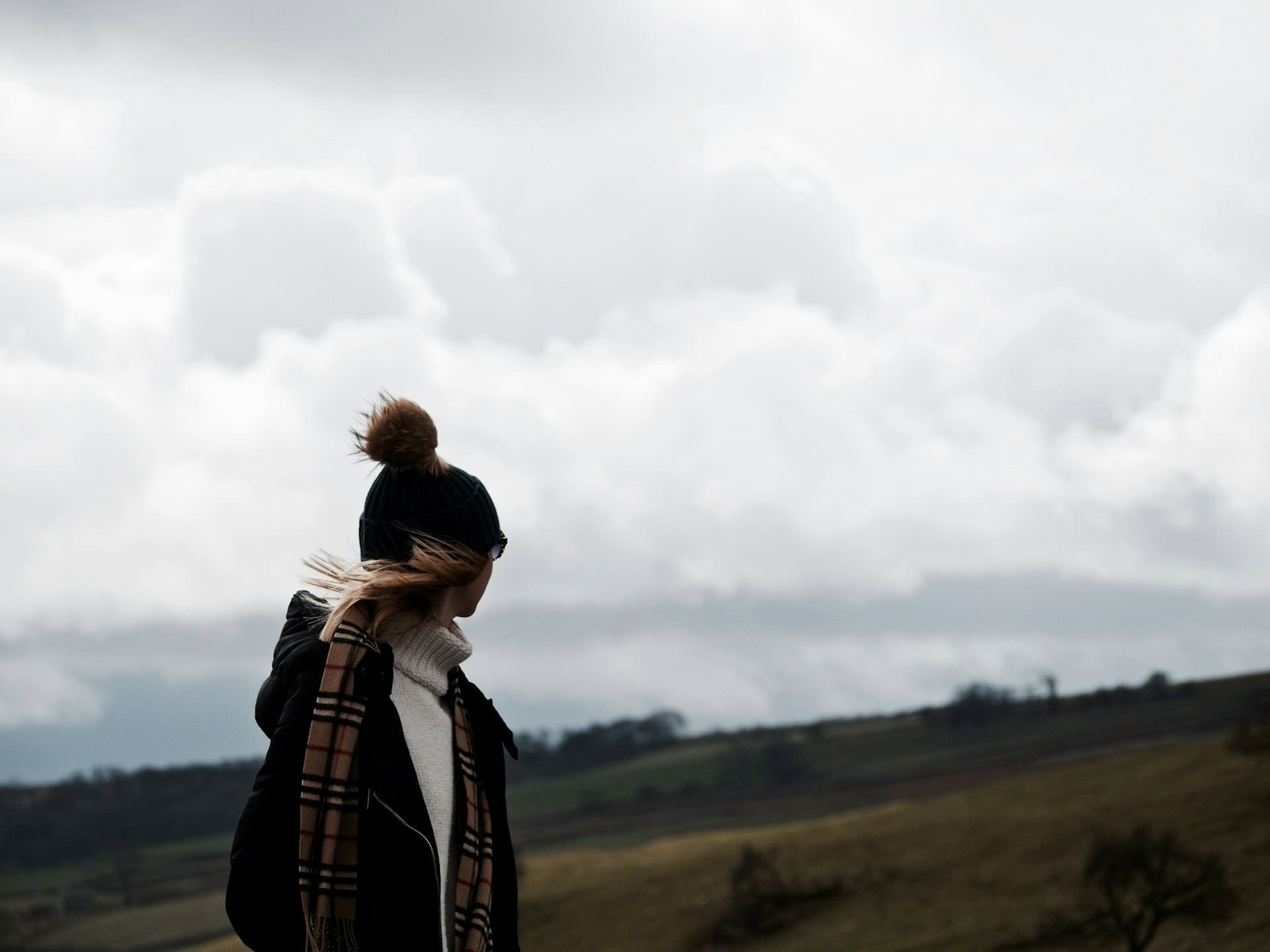 Woman standing on hill in strong wind