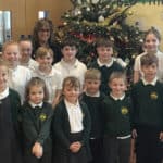 Pupils and teacher standing in front of Christmas tree at aWootton primary school