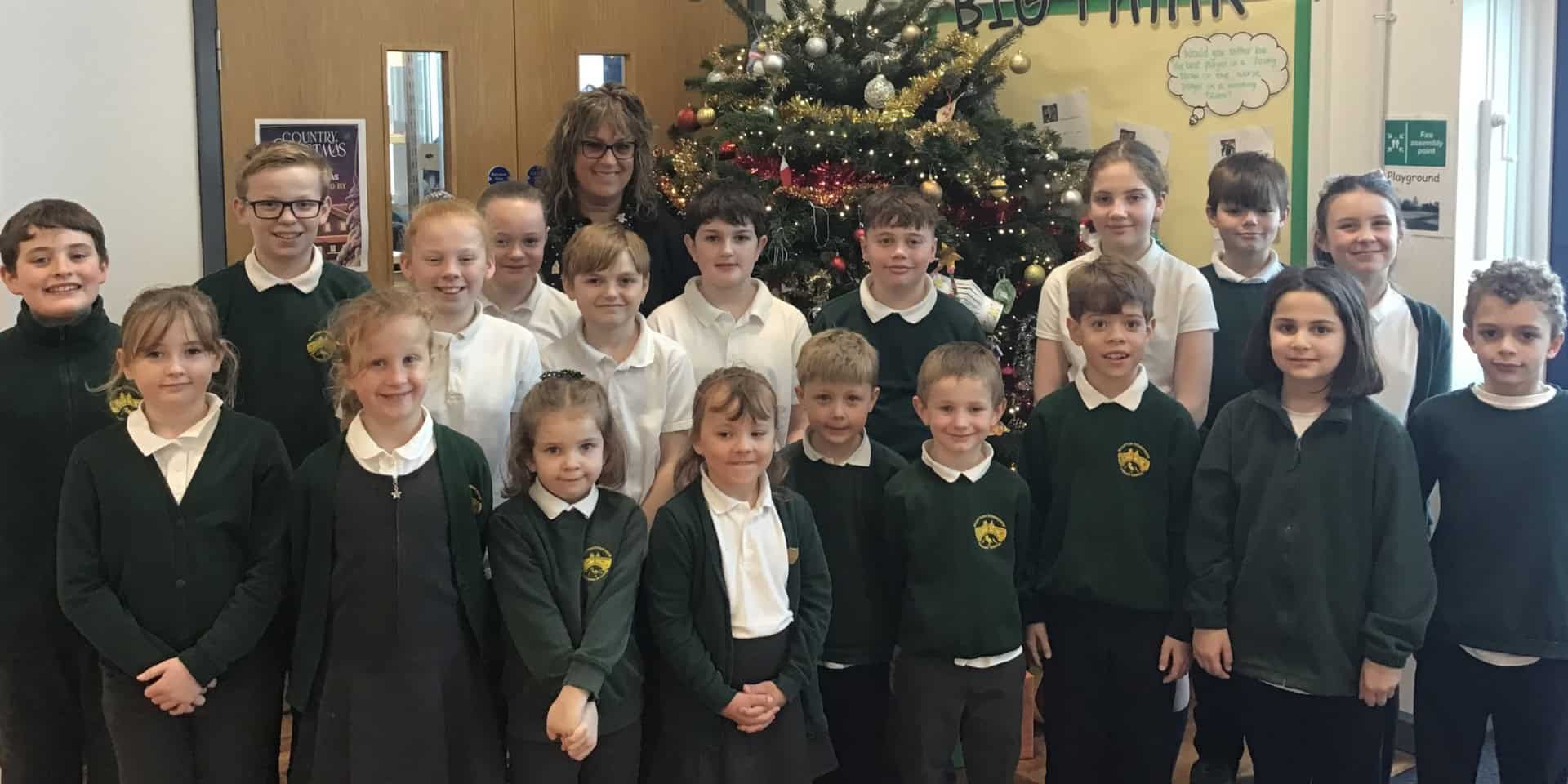 Pupils and teacher standing in front of Christmas tree at aWootton primary school