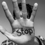 man holding out his hand with stop written on his palm