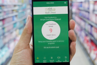 Person holding a mobile phone in a supermarket with Bank the food app