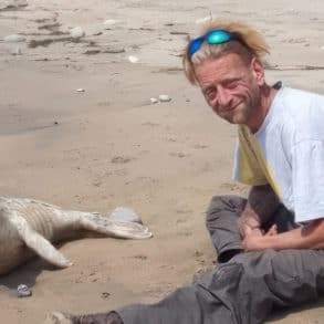 Jason Nicholls on the beach with a seal