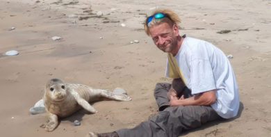 Jason Nicholls on the beach with a seal