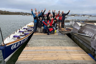 Old Harry wooden gig in the water with the Rowing crew on the pontoon