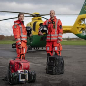 air ambulance crew standing in front of the helicopter with their bags