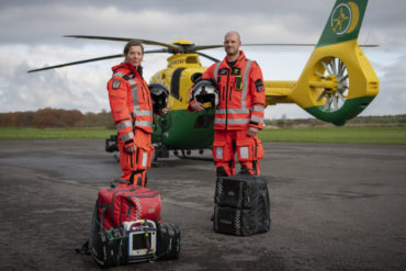 air ambulance crew standing in front of the helicopter with their bags