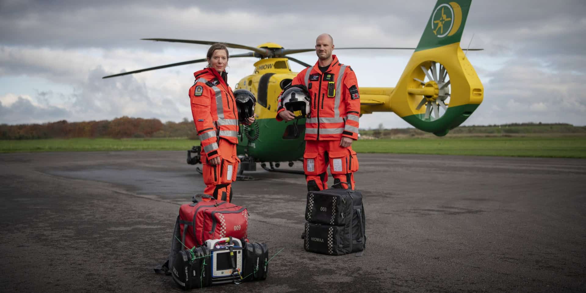 air ambulance crew standing in front of the helicopter with their bags