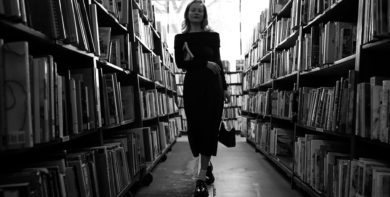 black and white photo of woman in library by anastasiya badun