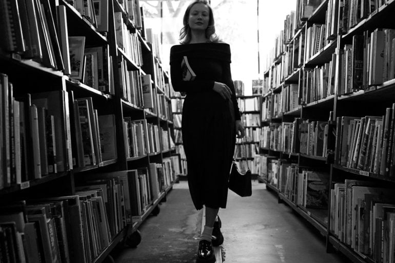 black and white photo of woman in library by anastasiya badun