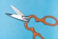 orange handled scissors on a blue background