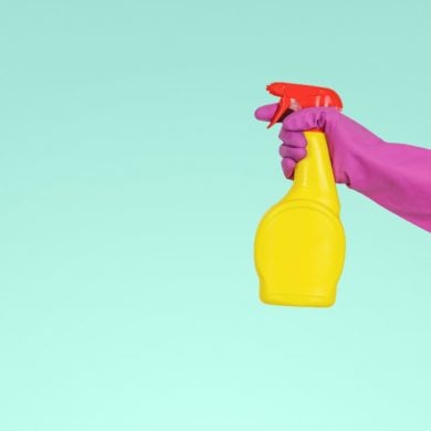 person with rubber gloves on holding a bottle of disinfectant