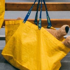 yellow ikea shopping bags hanging on hooks with teddy poking out of one