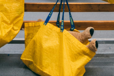 yellow ikea shopping bags hanging on hooks with teddy poking out of one