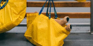 yellow ikea shopping bags hanging on hooks with teddy poking out of one