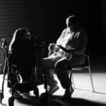 People sitting in darkened space with light coming in through the doorway