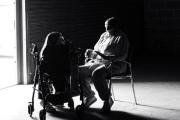 People sitting in darkened space with light coming in through the doorway