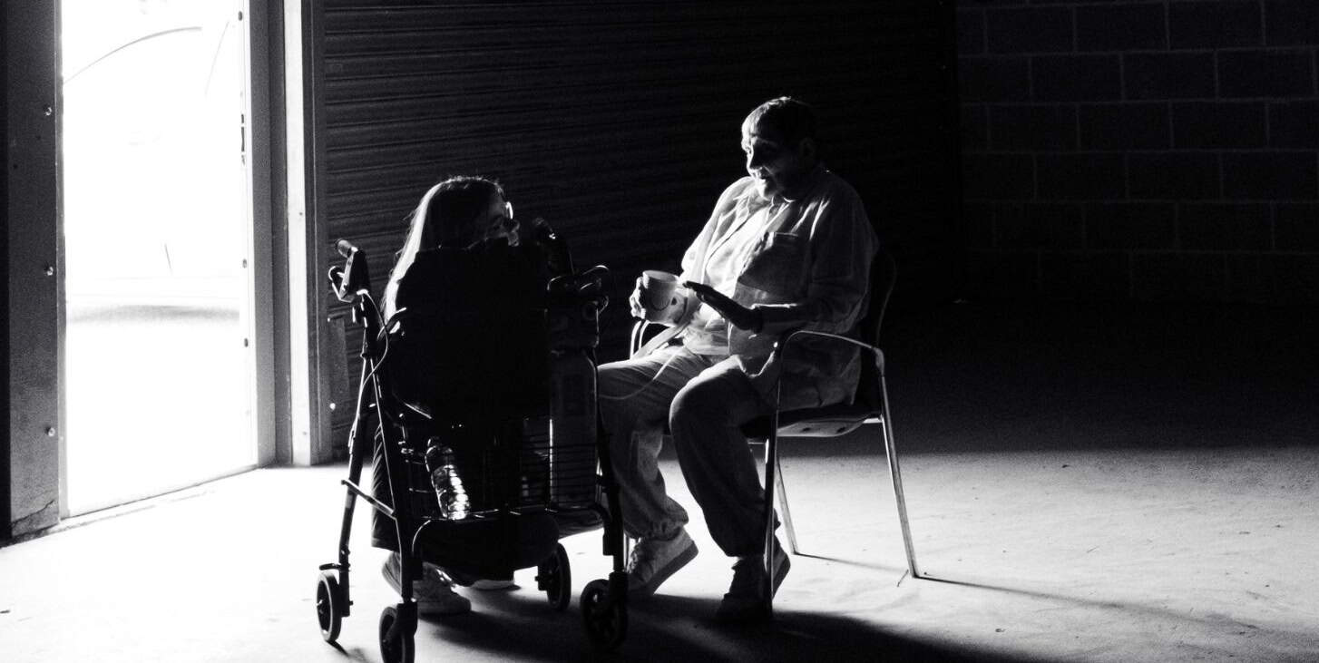 People sitting in darkened space with light coming in through the doorway