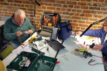 men working on electronics repairs at the repair cafe