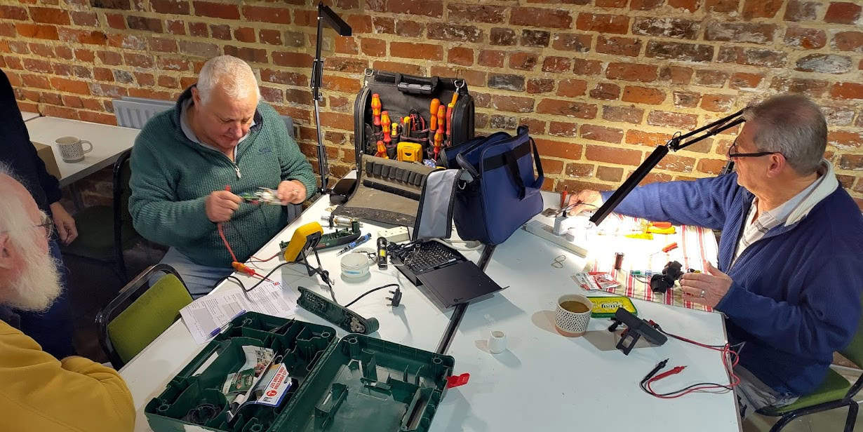 men working on electronics repairs at the repair cafe