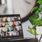 photo of laptop with zoom call in progress, green plant on desk and clock in the background