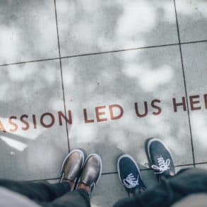 photo showing two people's feet with text on pavement reading ' passion led us here'