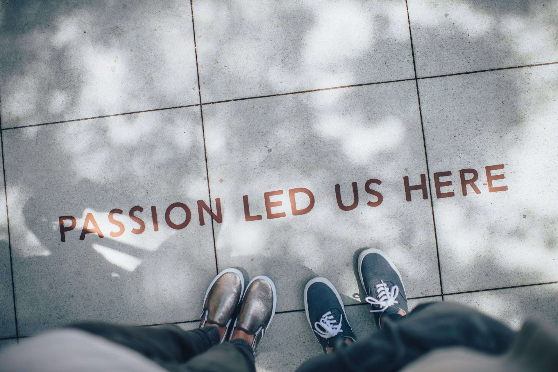 photo showing two people's feet with text on pavement reading ' passion led us here'