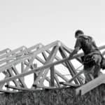 Man on timber framed house fitting the roof