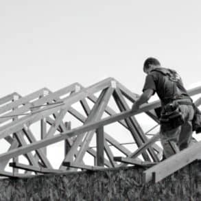 Man on timber framed house fitting the roof