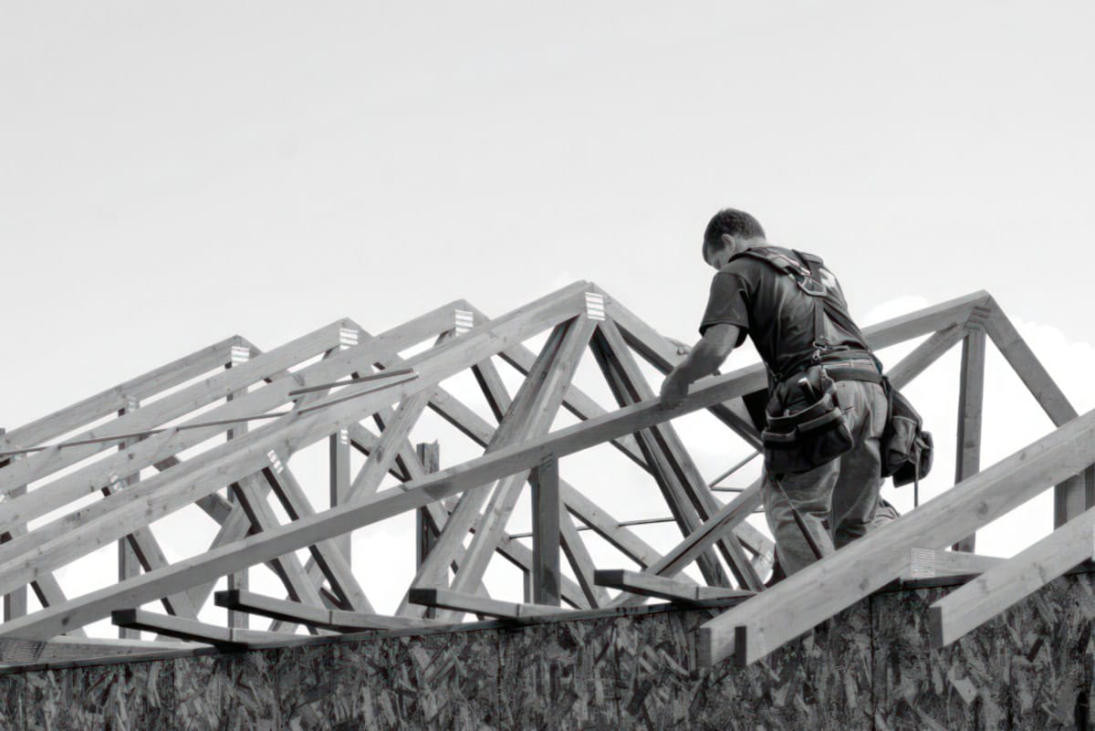 Man on timber framed house fitting the roof