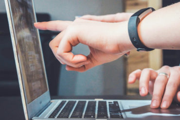 two people pointing at a laptop
