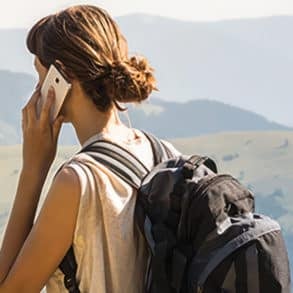 back of a woman in the mountains on a mobile phone