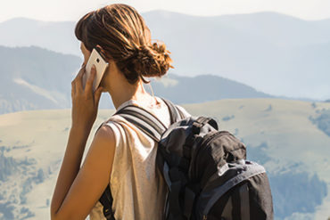 back of a woman in the mountains on a mobile phone