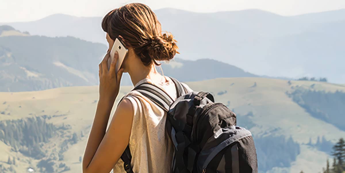 back of a woman in the mountains on a mobile phone