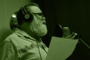 Paul singing in the recording studio - which a green light across the photo
