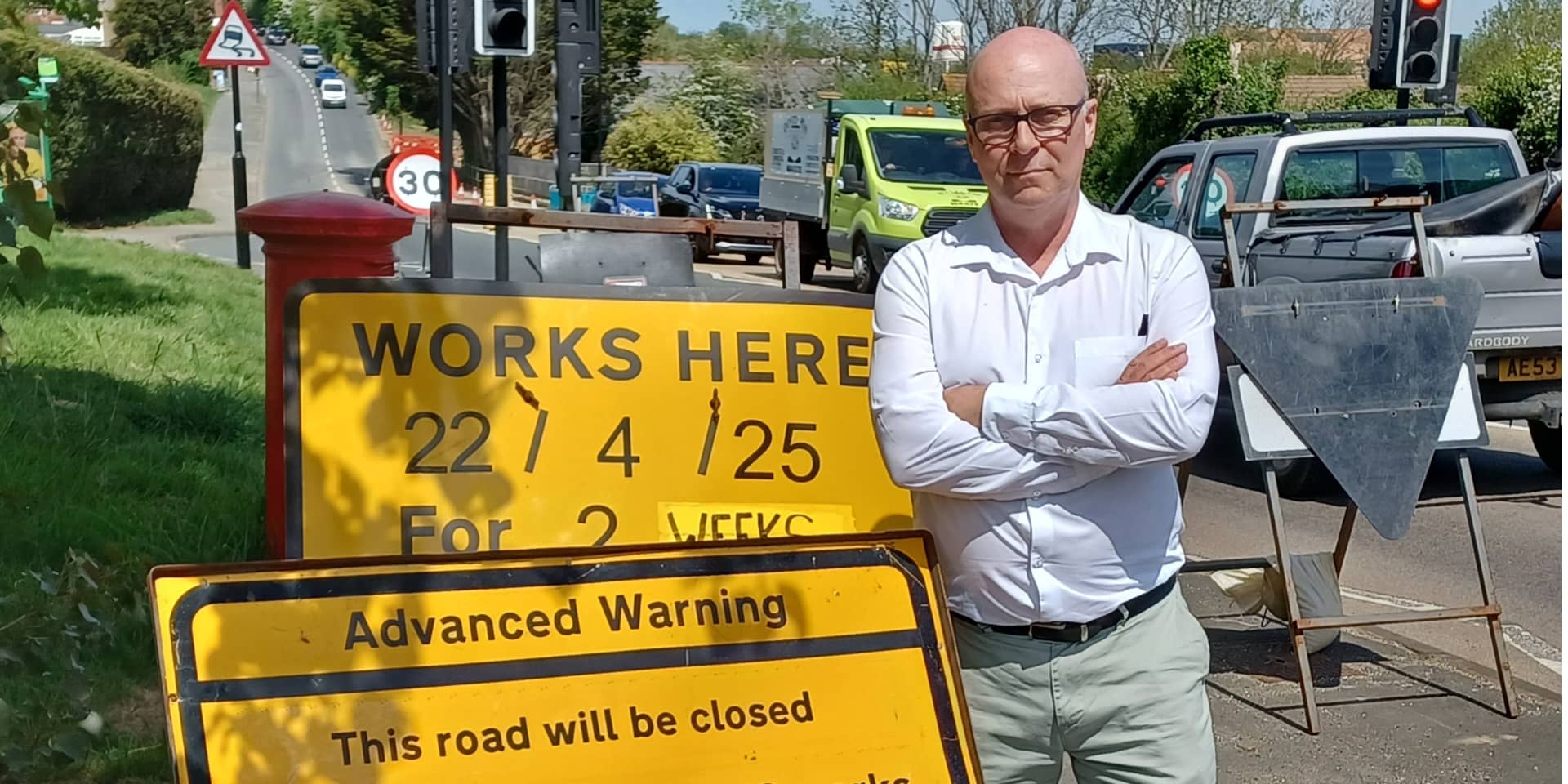 Andrew Garratt standing by road works sign