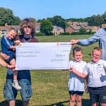 Parish Clerk Kirsty Gibson and Toby Jacobson, Contracts Manager, Trant Engineering Limited with a cheque for £1,000 with excited children who just happened to be on Stroud with their parents at the time