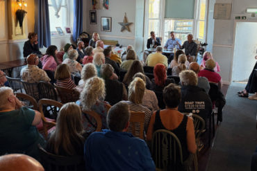 Photo of the Winter Gardens meeting at Better Days Cafe - shot from the back so you can only see the backs of people's heads and the three people on a table at the front